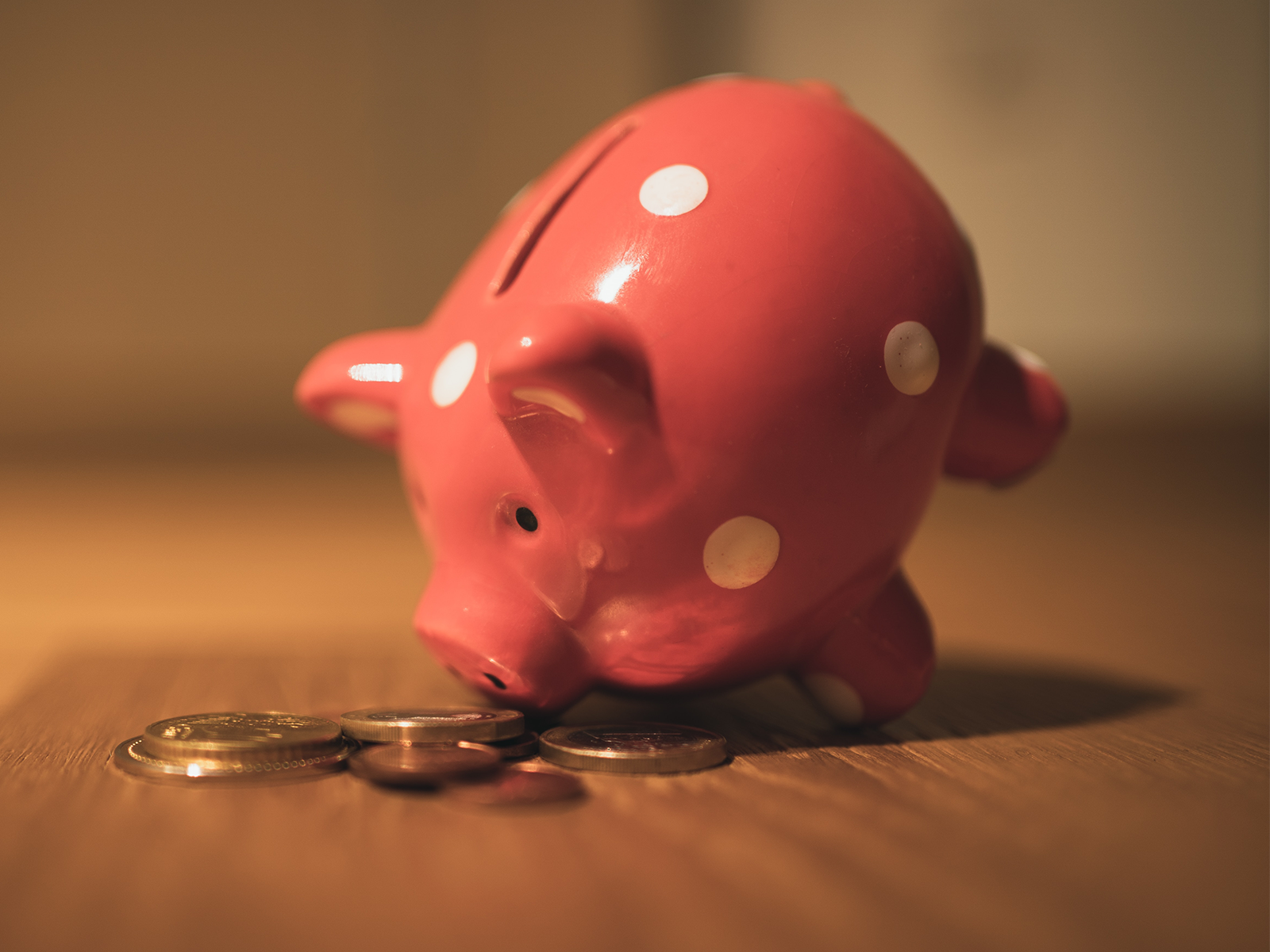 A pink piggie pank tilted onto its snout with coins extending.
